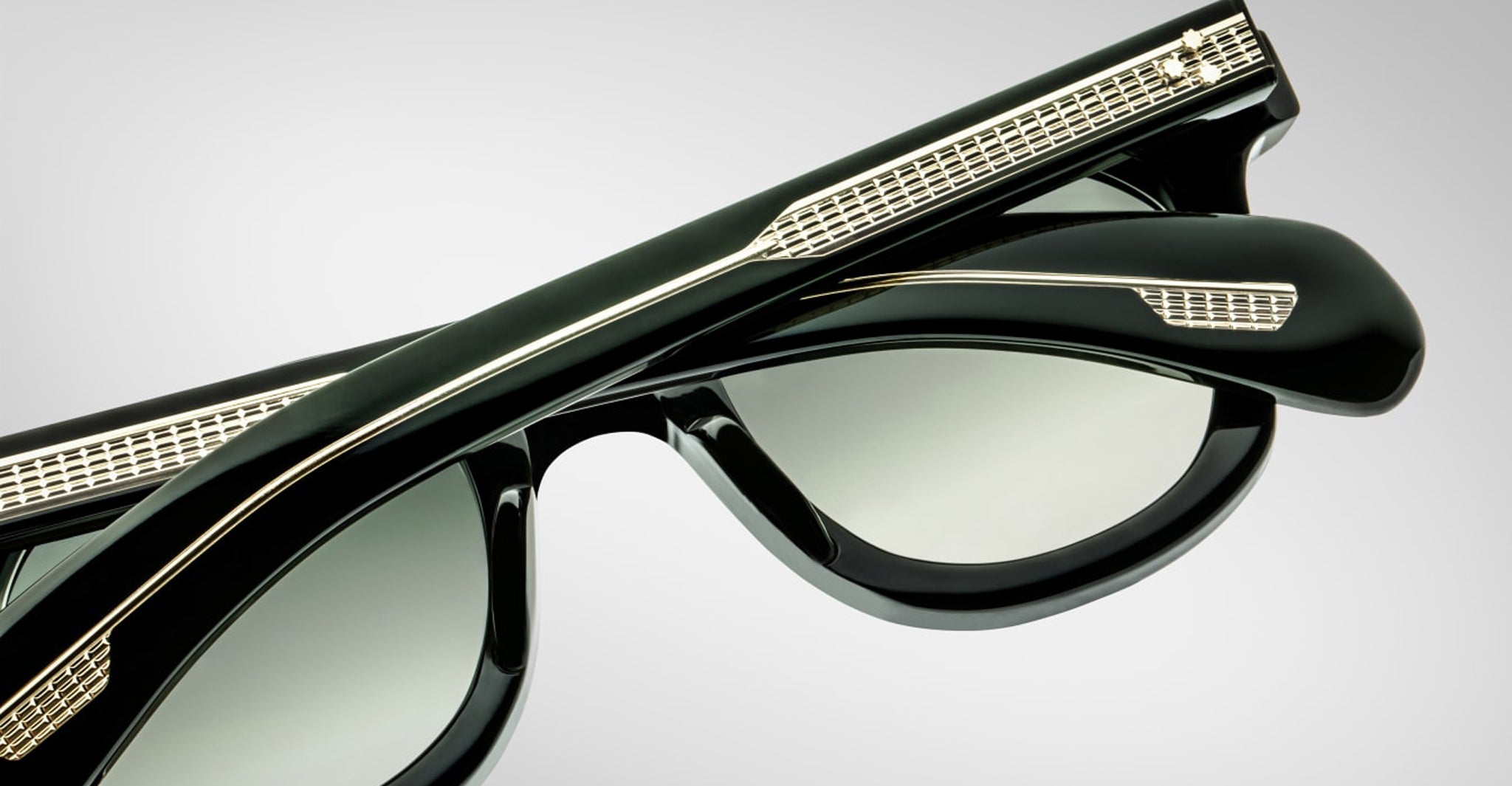 Close-up of two pairs of Jacques Marie Mage Vendome sunglasses with gold-detailed temples, stacked together against a plain background—expertly handcrafted in Japan.