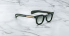 Jacques Marie Mage Vendome black sunglasses with dark lenses and gold-detailed arms, handcrafted in Japan, displayed on a white marble surface.