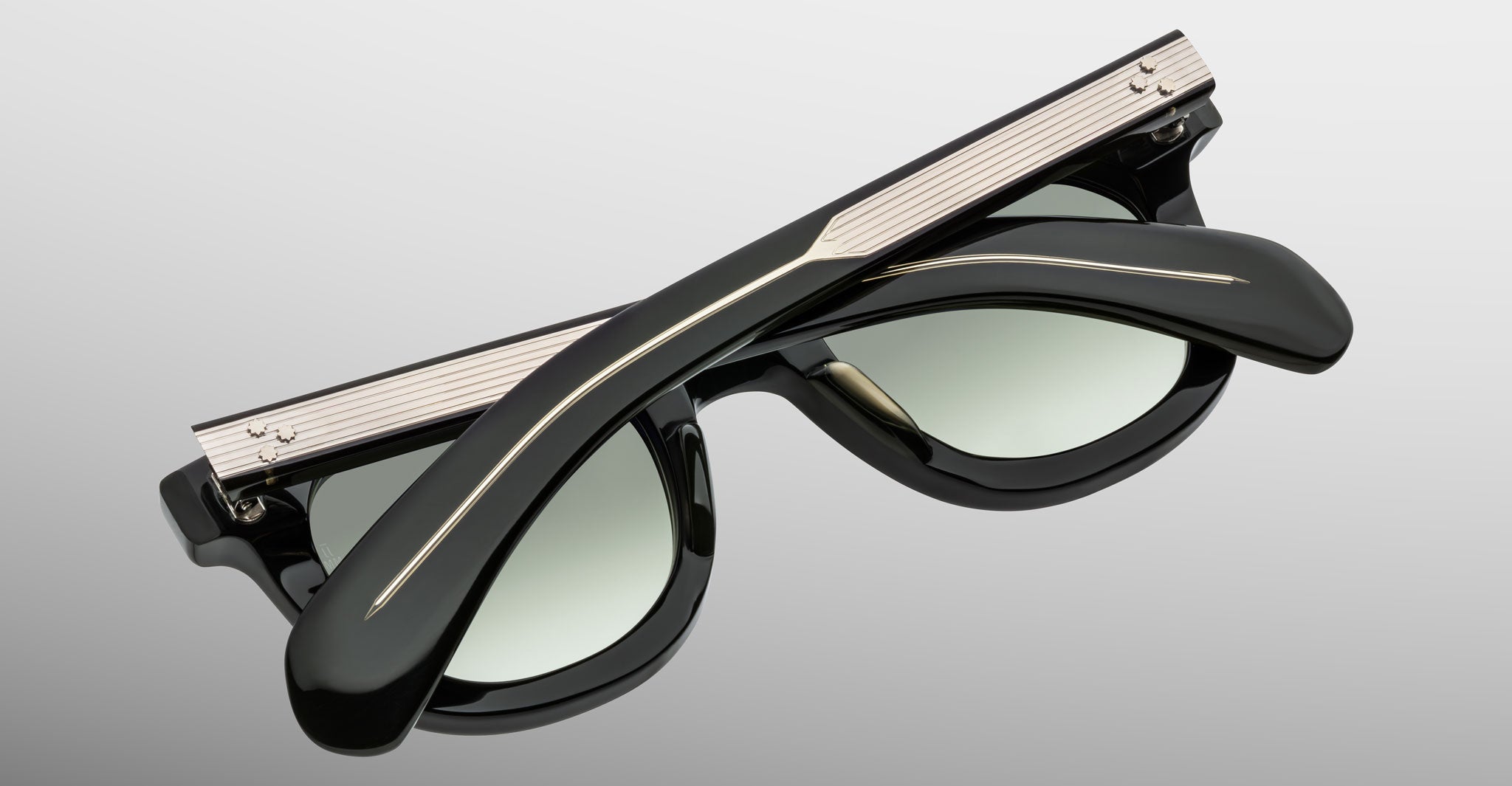 A pair of Jacques Marie Mage Vendome black sunglasses by Jacques Marie Mage, featuring metal accents and handcrafted in Japan, are folded and displayed on a light gray background.