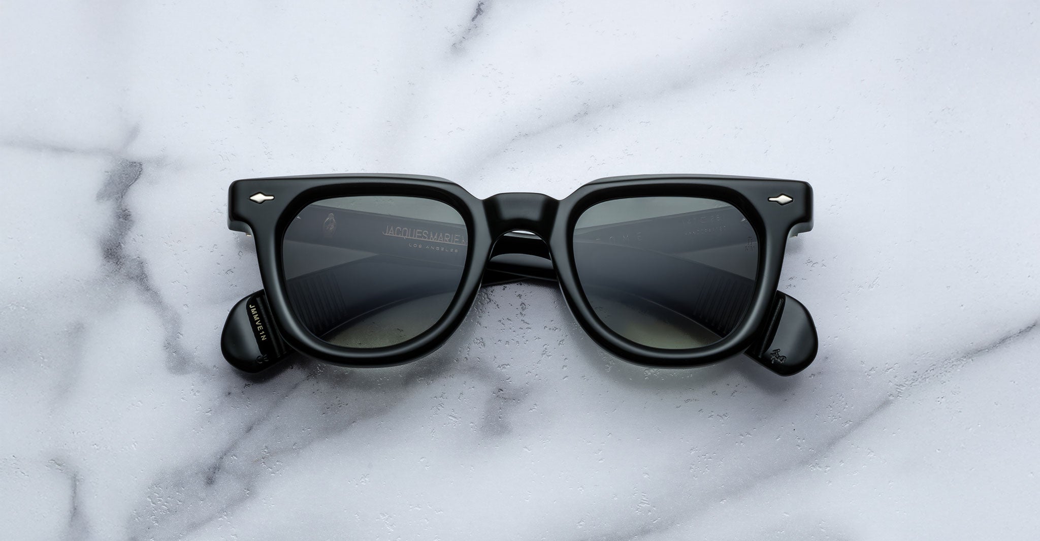 Jacques Marie Mage Vendome black rectangular sunglasses with dark lenses by Jacques Marie Mage, handcrafted in Japan, shown on a white marble surface.