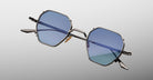 Jacques Marie Mage Verlaine hexagonal sunglasses with blue lenses and thin metal frames, shown from a front-facing angle.