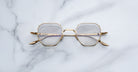 Jacques Marie Mage Verlaine gold-rimmed geometric eyeglasses with clear lenses shown from above.