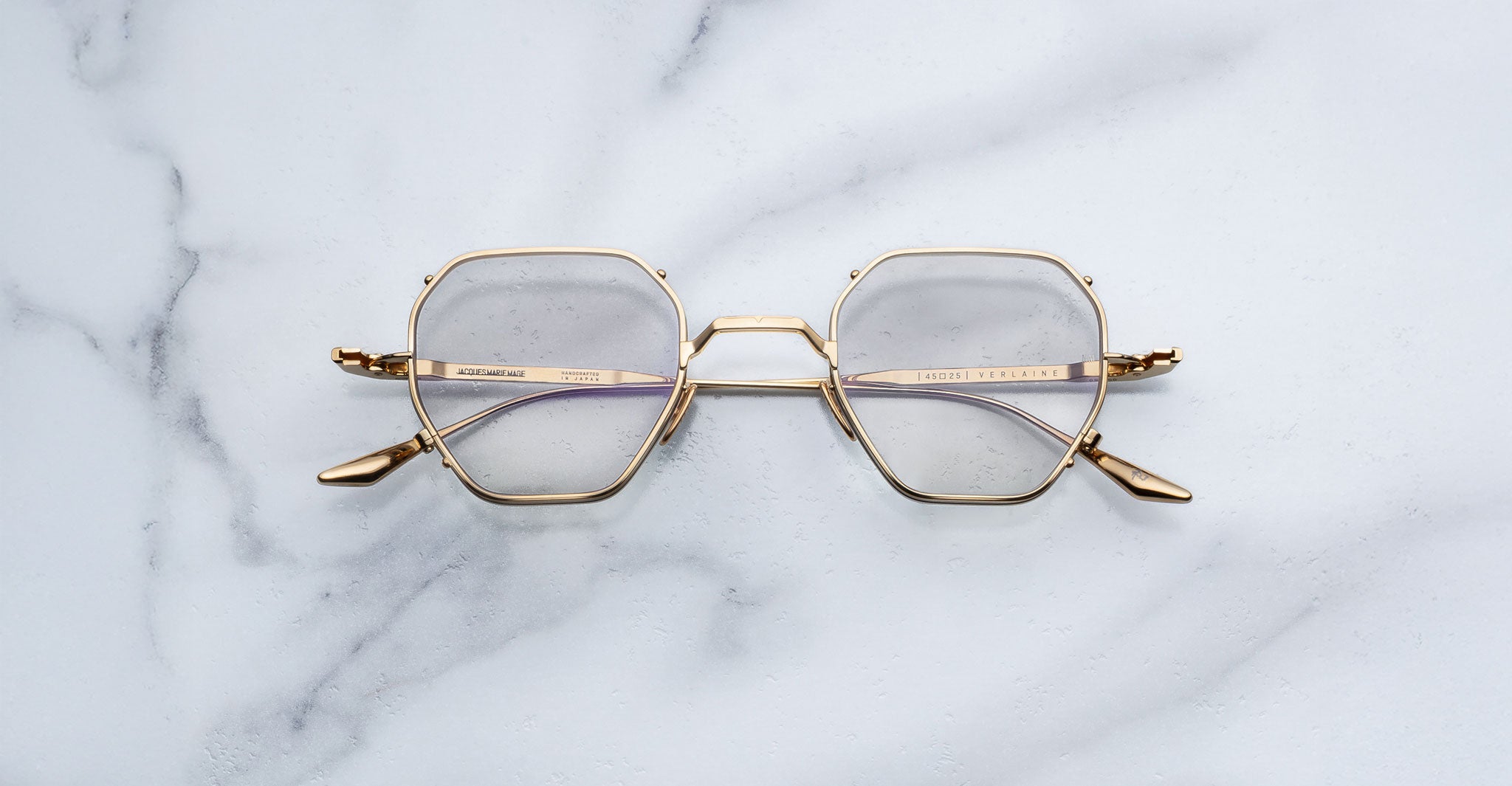 Jacques Marie Mage Verlaine gold-rimmed geometric eyeglasses with clear lenses shown from above.