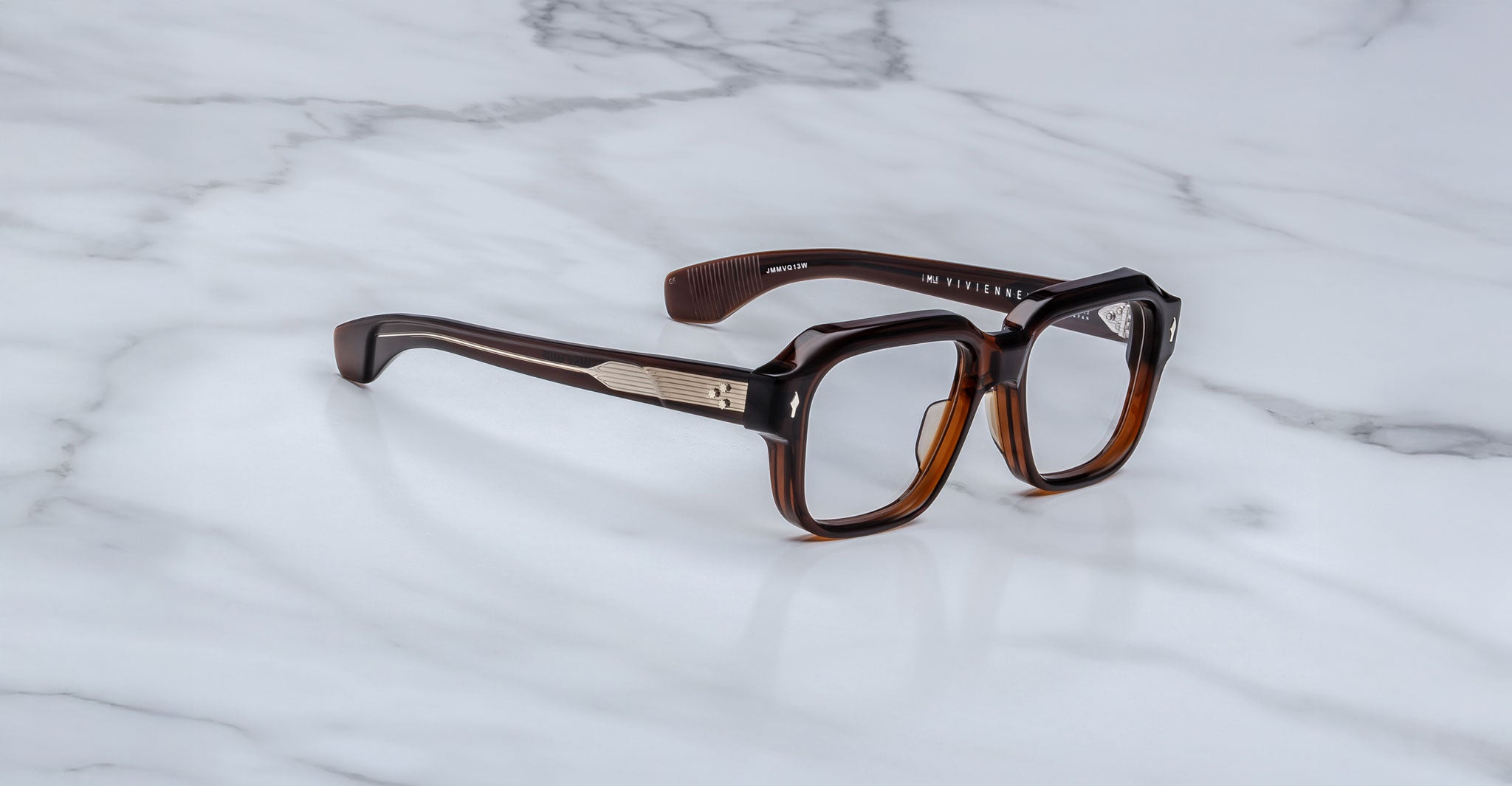 Jacques Marie Mage Vivienne square brown eyeglasses featuring silver accents on the arms, displayed on a white marble surface.