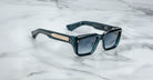 Jacques Marie Mage Walker blue rectangular sunglasses with thick frames and metallic accents, viewed from above.