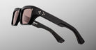 The Jacques Marie Mage Walker sunglasses feature thick rectangular black frames, dark tinted lenses, and small star-shaped accents on the arms, shown against a light gray gradient background.
