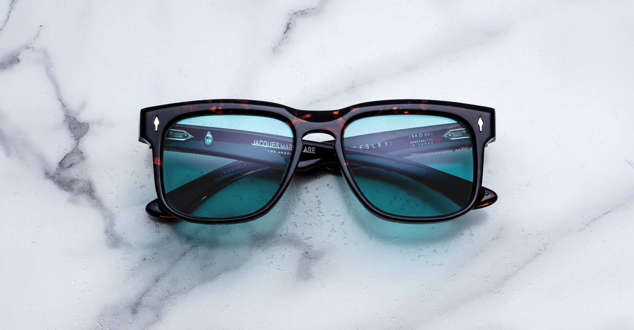 Jacques Marie Mage Wesley sunglasses with blue lenses and rounded arms, shown from above.