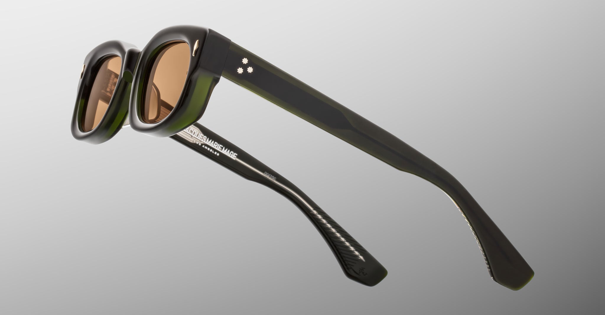Jacques Marie Mage Whiskeyclone in Borneo, dark green acetate sunglasses with translucent olive green accents, warm amber-tinted lenses, signature three-dot silver-tone rivets, and sculpted temples, shown from a rear side angle highlighting the layered acetate construction and Jacques Marie Mage branding on the inner temple