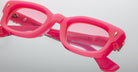 Close-up view of Jacques Marie Mage Whiskeyclone eyeglasses—thick, rectangular frames in bright pink with pink-tinted lenses—shown on a white background. Brand and model details are visible inside the frame.