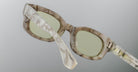 Close-up view of Jacques Marie Mage Whiskeyclone eyeglasses with translucent, marbled frames and light green-tinted lenses, highlighting the frame’s detailed texture against a plain gray background.