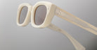 Close-up of Jacques Marie Mage Whiskeyclone sunglasses featuring stylish, chunky white frames and gray-tinted lenses, set against a plain light background.