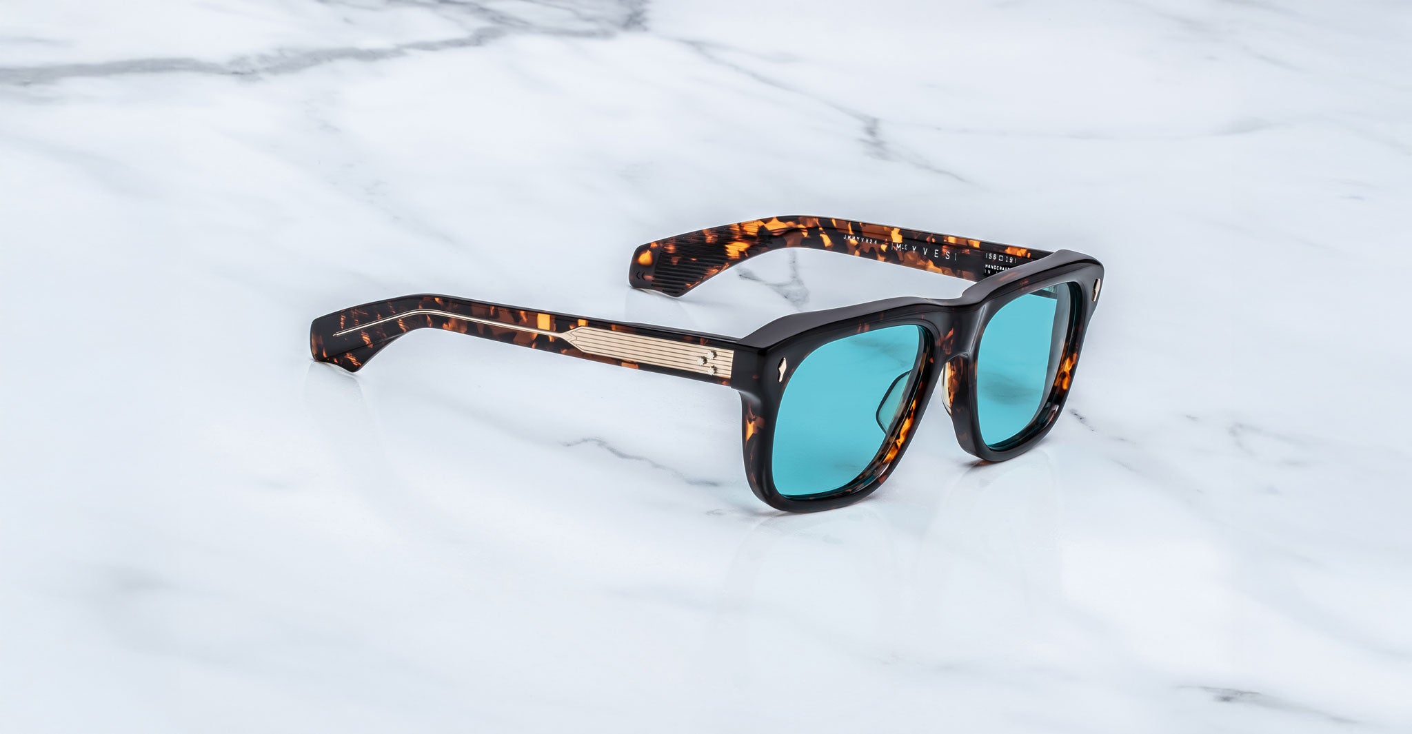 Jacques Marie Mage Yves sunglasses with teal lenses, viewed from above, displayed on a flat surface.