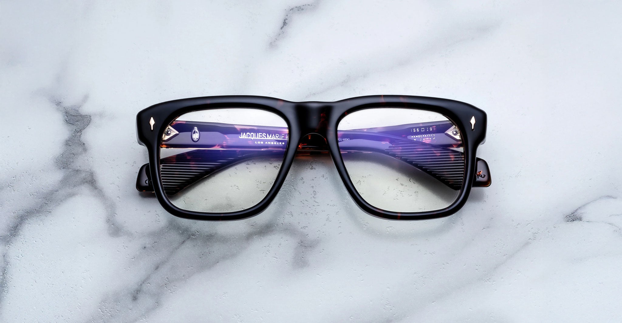 Jacques Marie Mage Yves black eyeglasses, front view, with subtle reflections on lenses.