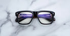 Jacques Marie Mage Yves black eyeglasses, front view, with subtle reflections on lenses.