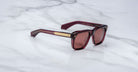 Jacques Marie Mage Yves burgundy square sunglasses with gold-accented arms, front and side view.
