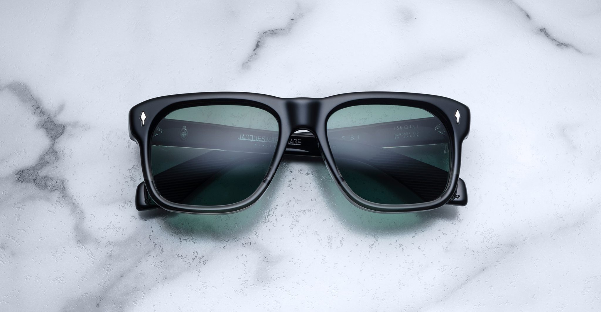 Jacques Marie Mage Yves black rectangular sunglasses with green lenses, shown from above.