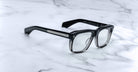 Jacques Marie Mage Yves black eyeglasses with clear lenses, classic design, shown from above.
