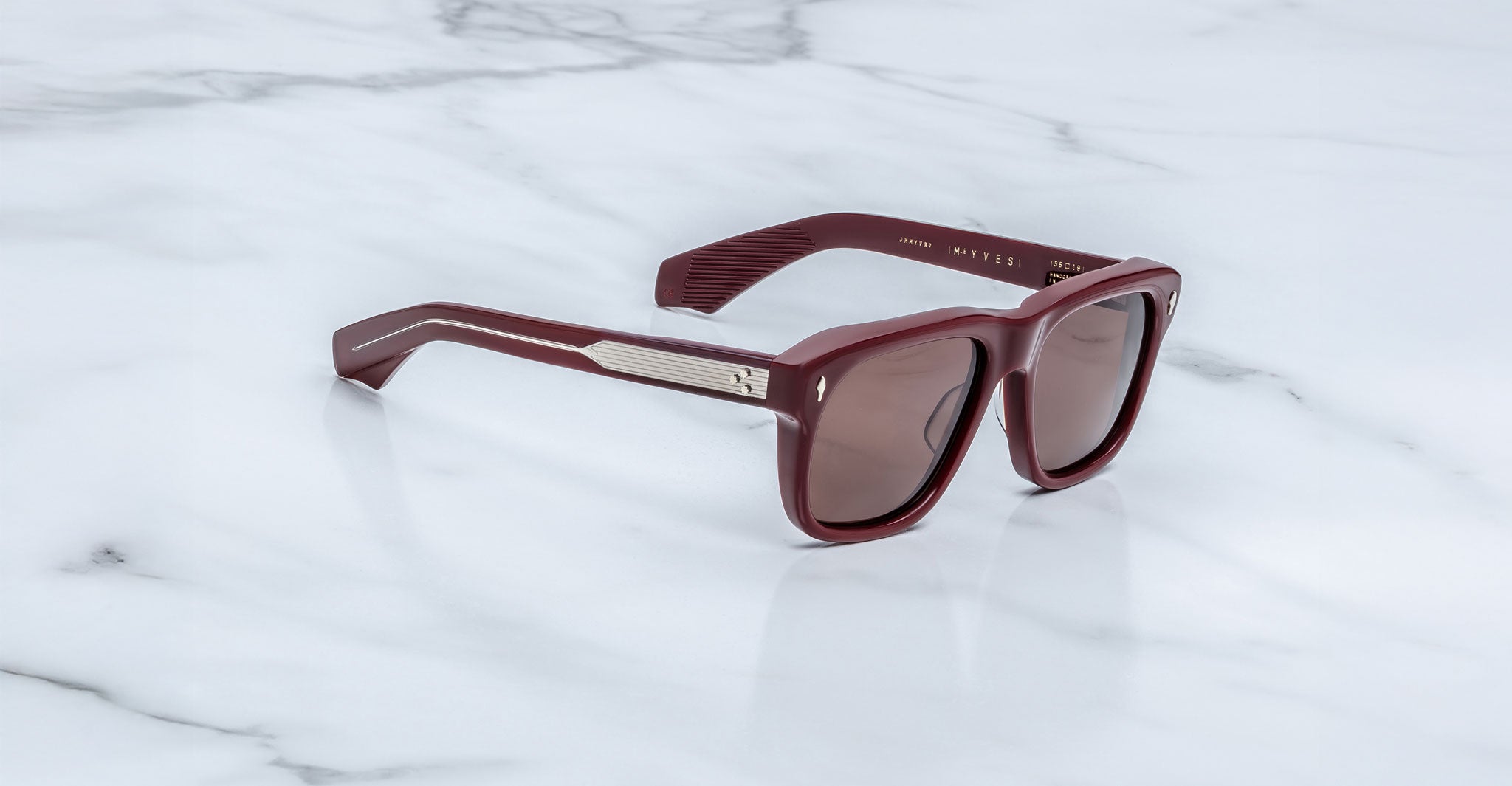 Jacques Marie Mage Yves in Bordeaux Empire sunglasses, rectangular deep red acetate frame with rose-tinted lenses, signature arrowhead rivets, and exposed engraved metal core temples, angled side view