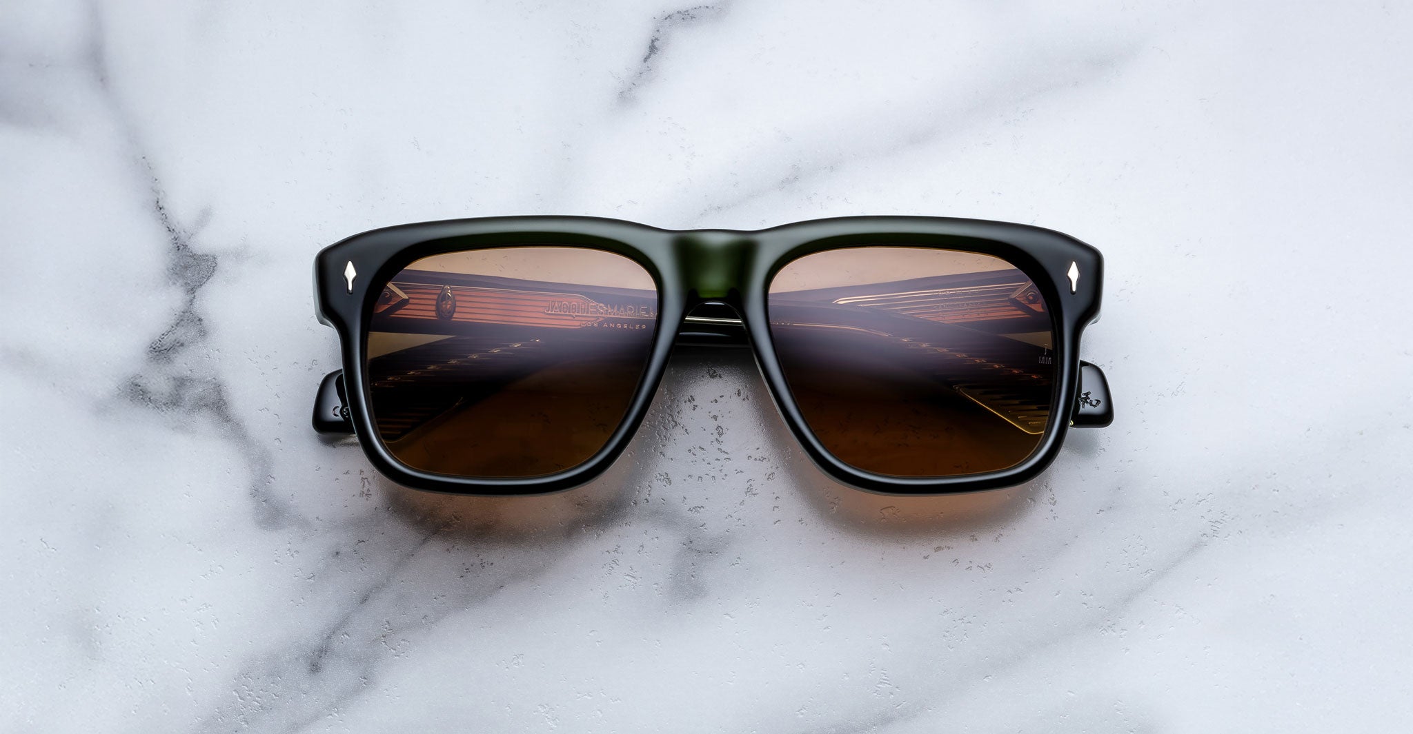 Jacques Marie Mage Yves black sunglasses with brown lenses, top view showing piano key reflections.