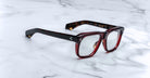 Jacques Marie Mage Yves rectangular dark red tortoiseshell eyeglasses with clear lenses, top view.