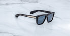 Jacques Marie Mage Yves in Lacquer Blue sunglasses, rectangular dark blue acetate frame with blue-tinted lenses, signature arrowhead rivets, and engraved metal core temples, angled side view