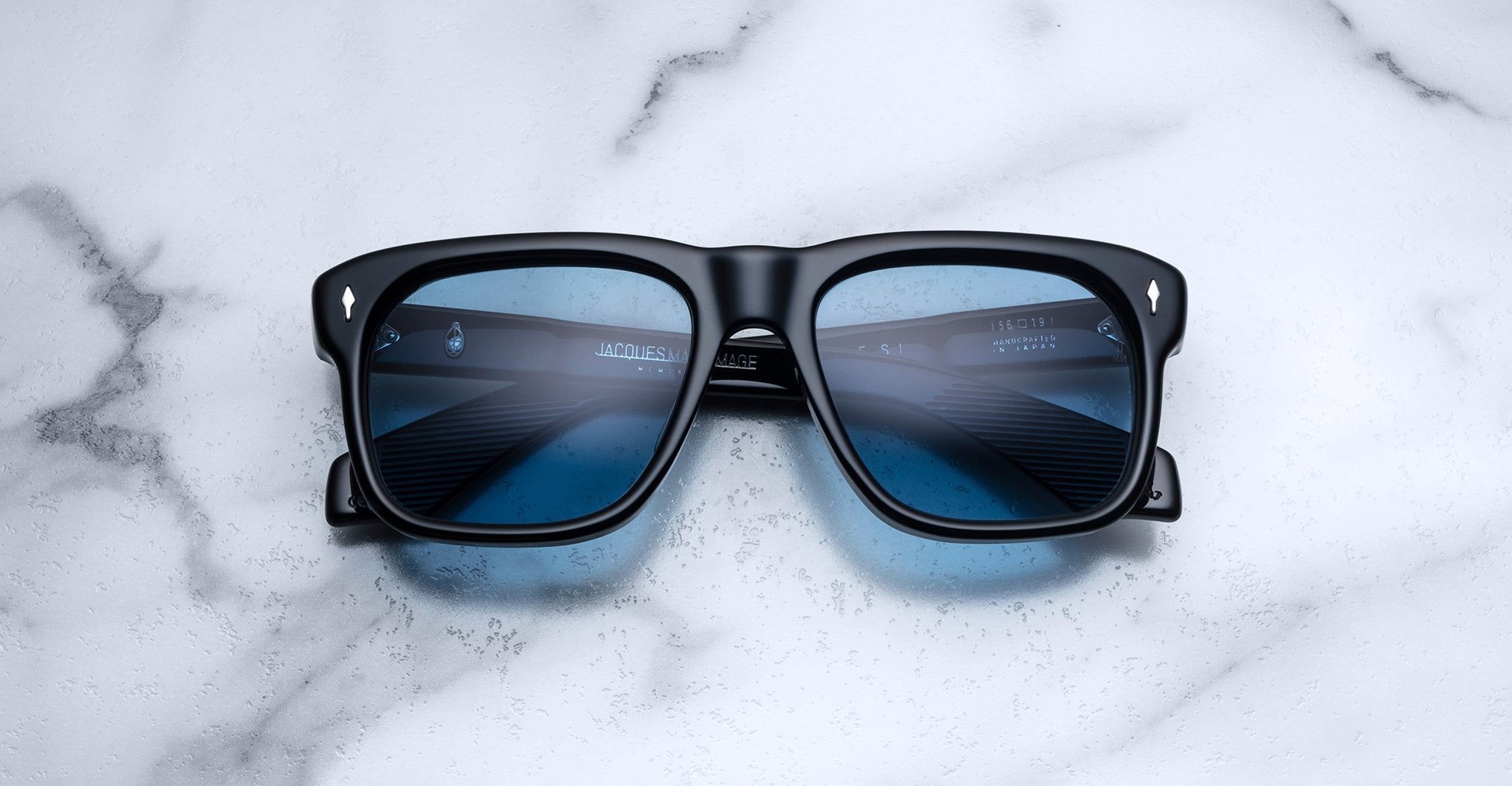 Jacques Marie Mage Yves sunglasses, black square frames with blue-tinted lenses, front view.