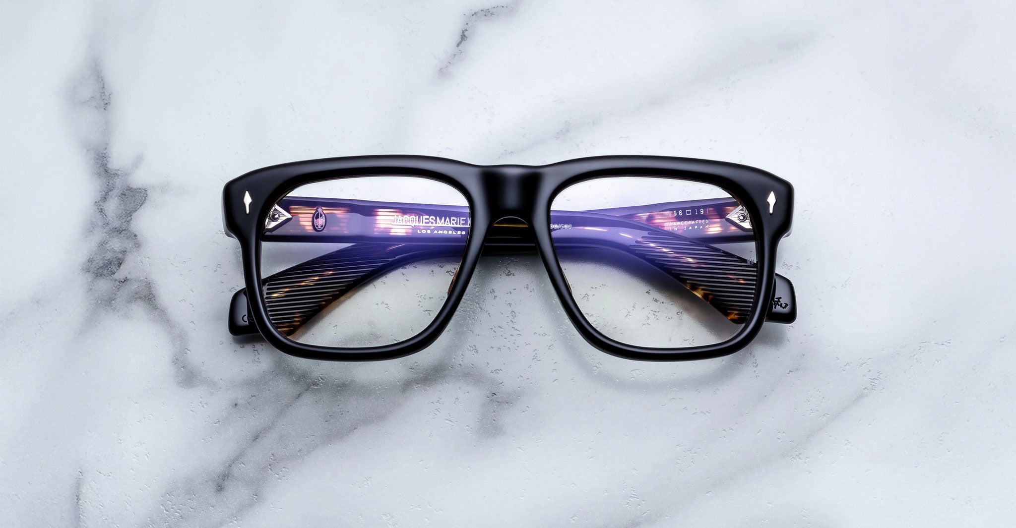 Jacques Marie Mage Yves black eyeglasses with thick frames, front view showing lens reflections.
