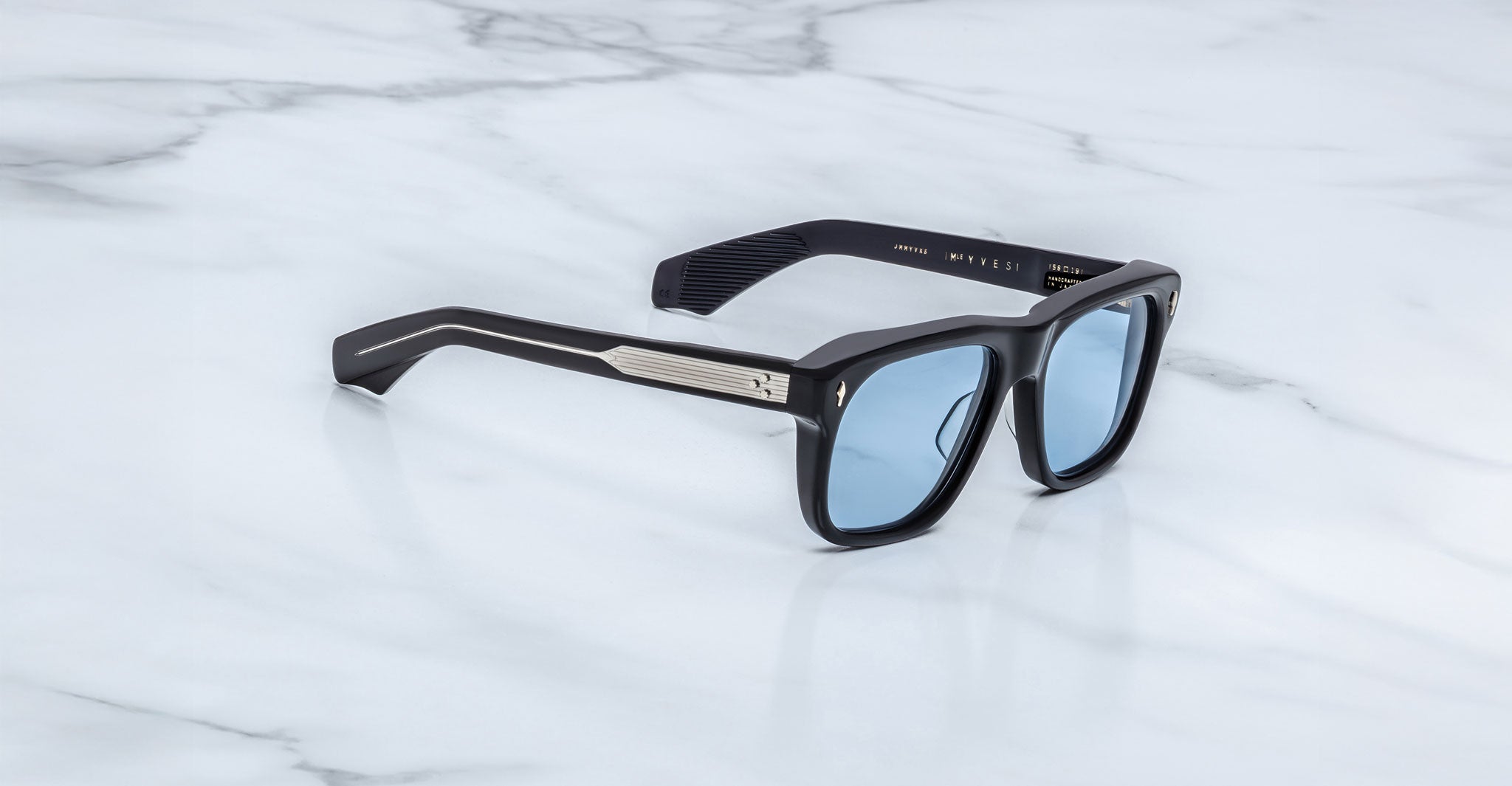 Jacques Marie Mage Yves in Obscure Black sunglasses, rectangular matte black acetate frame with blue-tinted lenses, signature arrowhead rivets, and engraved metal core temples, angled side view