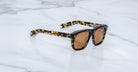Jacques Marie Mage Yves in Tokyo sunglasses, rectangular black acetate frame with yellow tortoise pattern and amber-tinted lenses, signature arrowhead rivets, angled side view