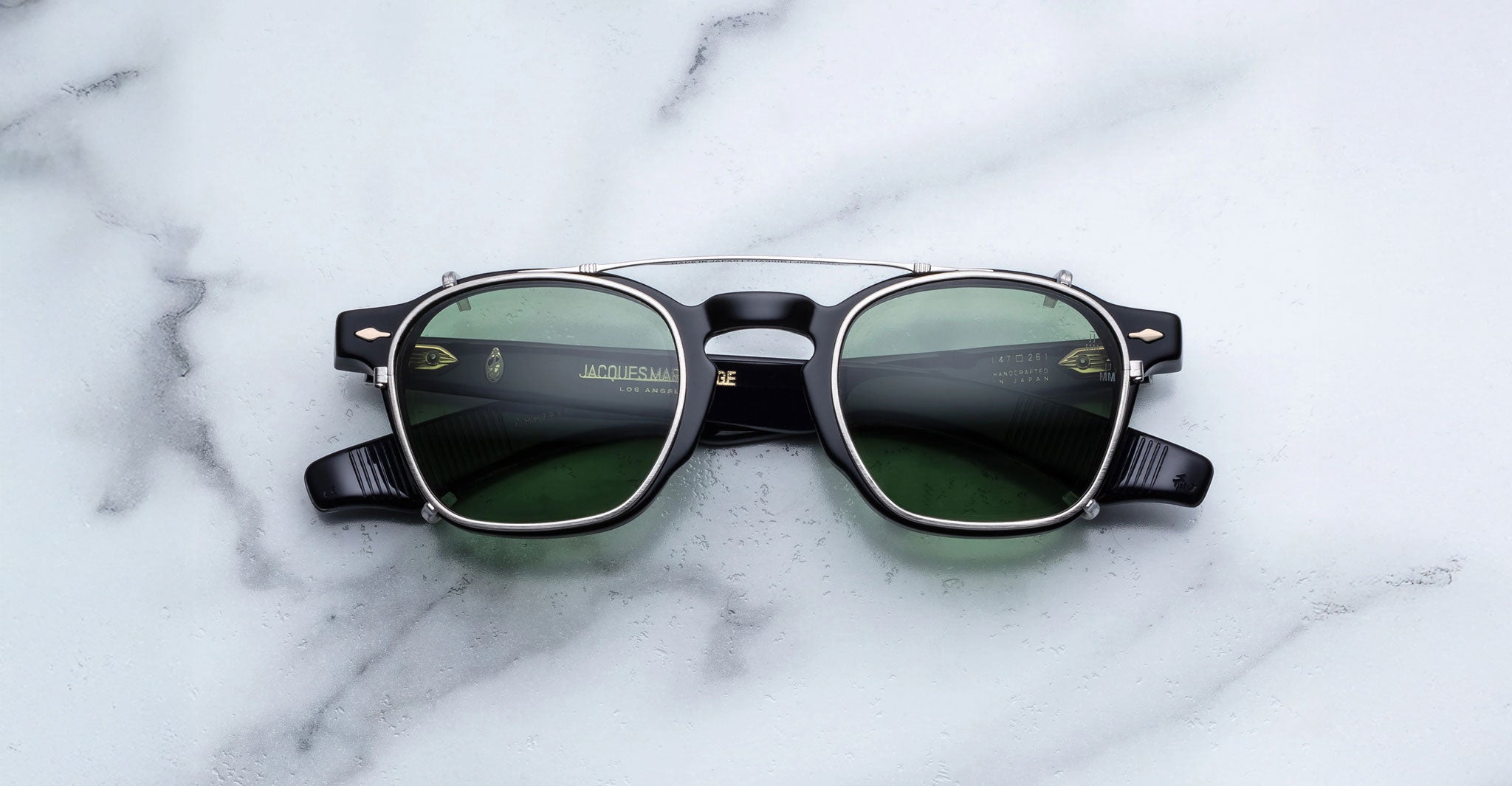 Jacques Marie Mage Zephirin 47 Clip On 2 sunglasses, black and silver frame with green lenses, shown from above.