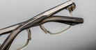 Close-up of two Jacques Marie Mage Zephirin 47 eyeglasses in translucent brown and clear frames, side-by-side, top view.