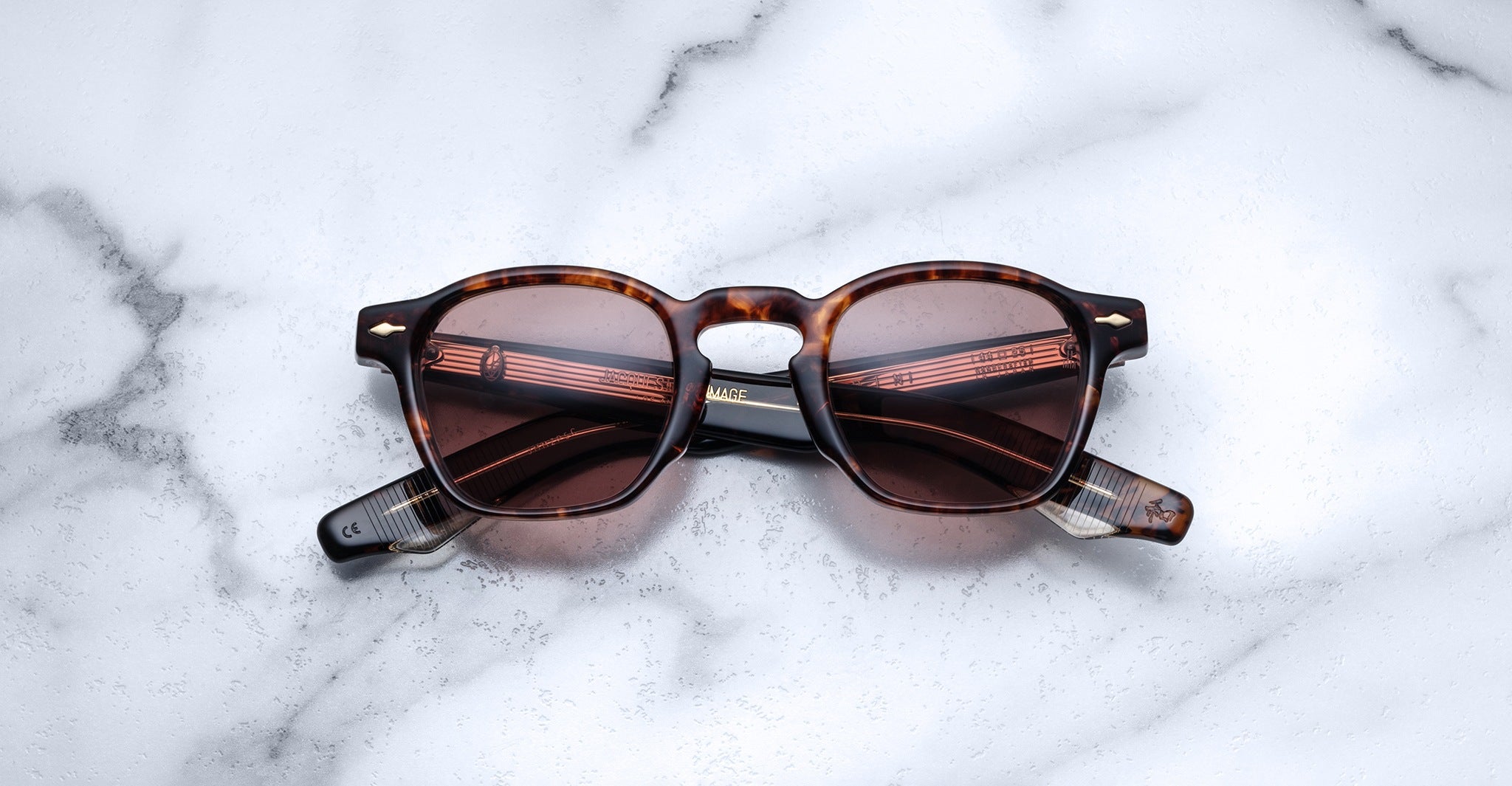 Jacques Marie Mage Zephirin sunglasses in brown tortoiseshell with dark lenses rest closed on white marble, highlighting the exclusivity of this limited edition eyewear.