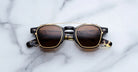 Jacques Marie Mage Zephirin Clip On 2 sunglasses with gold and black frames, viewed from above.