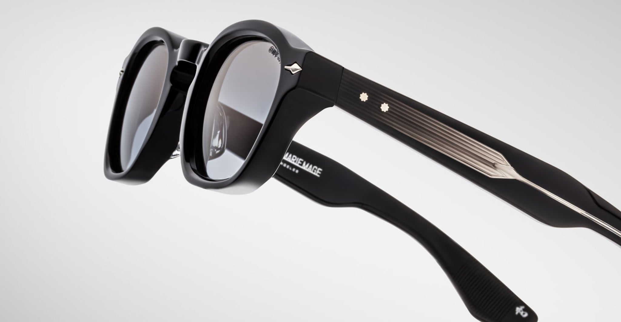 Close-up of Jacques Marie Mage Zephirin sunglasses—black, handcrafted acetate frames with metallic accents and decorative studs, by Jacques Marie Mage.