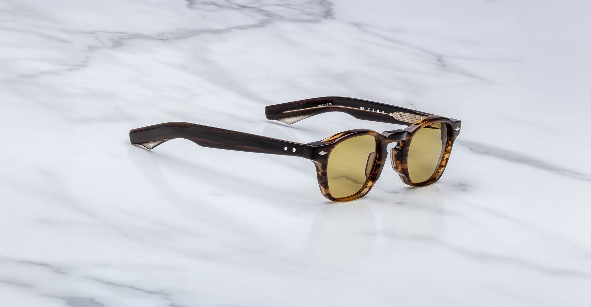 Jacques Marie Mage Zephirin sunglasses, featuring brown tortoiseshell acetate frames and round yellow-tinted lenses, rest on white marble—a limited edition piece for discerning collectors.