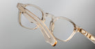Close-up of Jacques Marie Mage Zephirin transparent beige acetate spectacles, highlighting the handcrafted side arm and hinge, inspired by the iconic limited edition eyewear style, set against a neutral background.