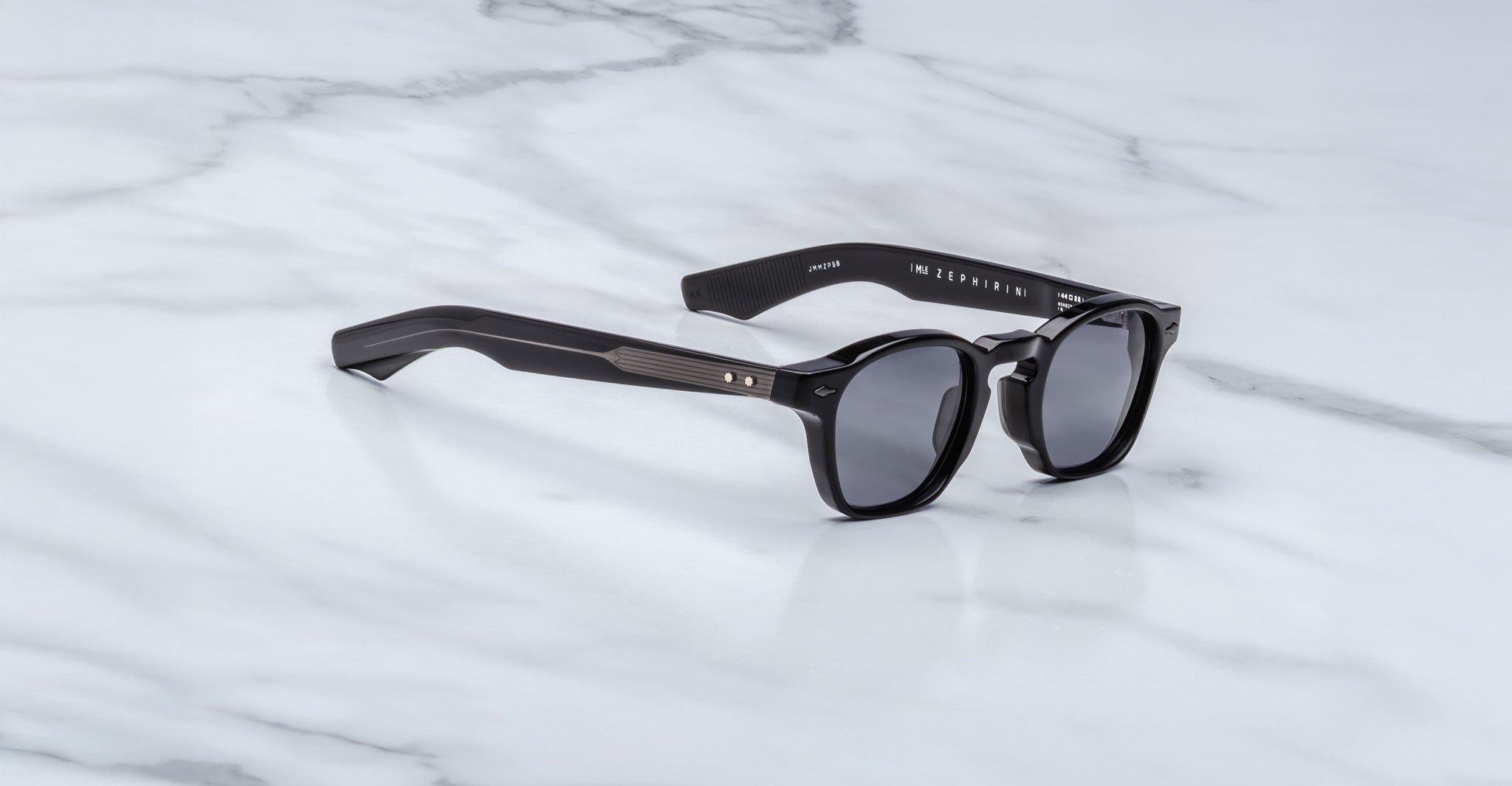 Jacques Marie Mage Zephirin sunglasses with round lenses and thick handcrafted acetate frames rest on a white marble surface, embodying the iconic style of Jacques Marie Mage.