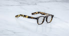 A pair of handcrafted Jacques Marie Mage Zephirin acetate spectacles rest elegantly on a white marble surface.