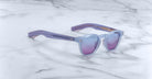 Jacques Marie Mage Zephirin sunglasses in light purple with tinted lenses are displayed on white marble—a striking, limited edition eyewear piece by Jacques Marie Mage.