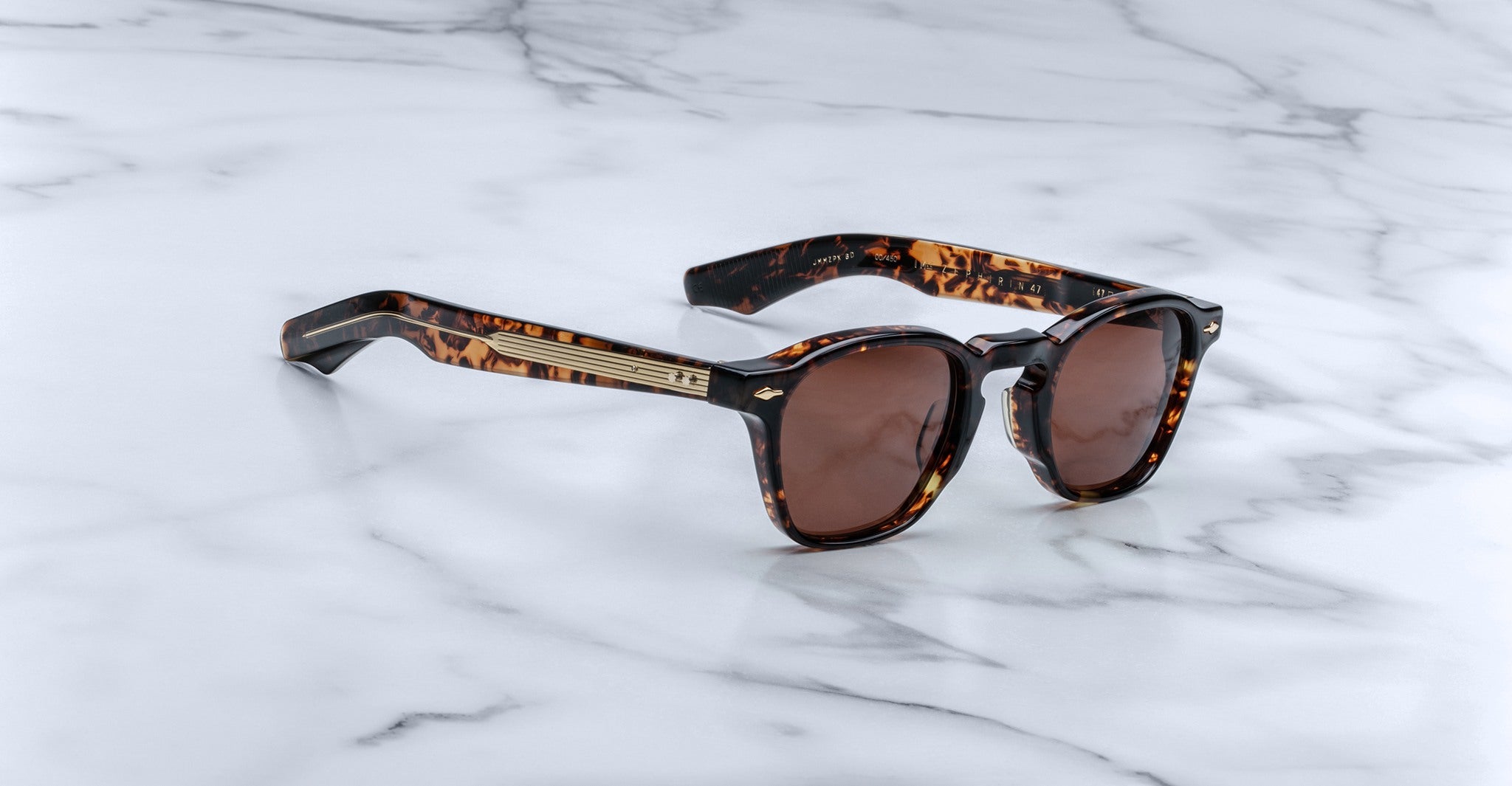 Jacques Marie Mage Zephirin 47 sunglasses, featuring brown lenses and gold accents, shown from above.