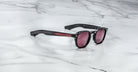 Jacques Marie Mage Zephirin 47 sunglasses with red arms and tinted lenses shown from above.