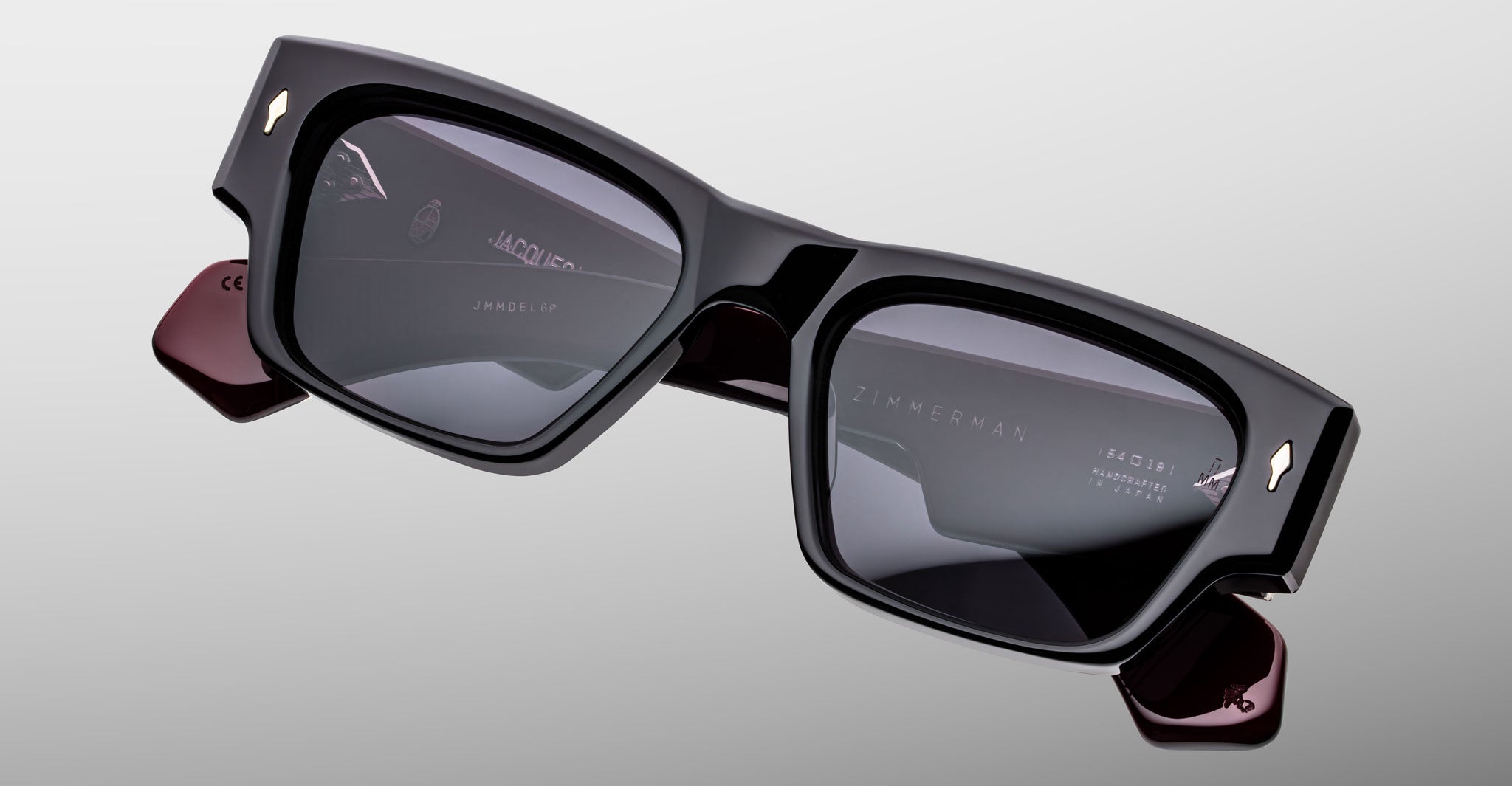 Jacques Marie Mage Zimmerman sunglasses in Bloodstone black acetate with bold rectangular frame, dark tinted lenses, and signature arrowhead front pins, angled front view