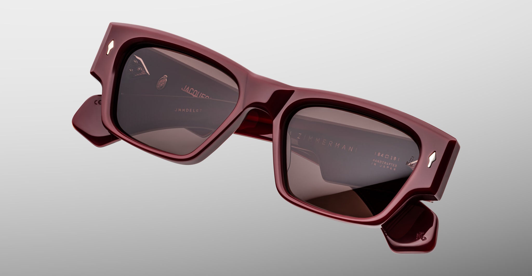 Jacques Marie Mage Zimmerman sunglasses in Bordeaux Empire red acetate with bold rectangular frame, brown tinted lenses, and signature arrowhead front pins, angled front view