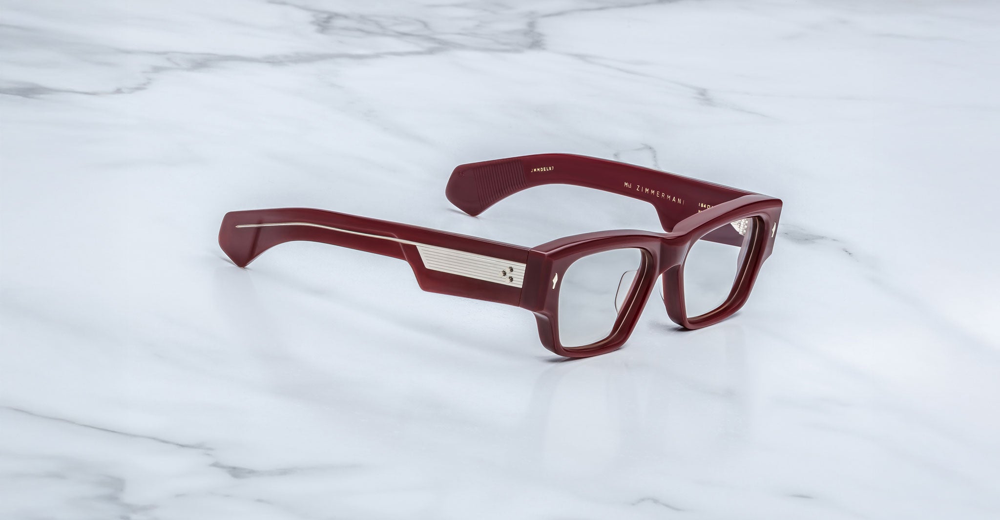 Jacques Marie Mage Zimmerman optical glasses in Bordeaux Empire red acetate with bold rectangular frame, clear lenses, and wide temples with signature metal core detail, angled view