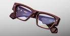Jacques Marie Mage Zimmerman optical glasses in Bordeaux Empire red acetate with bold rectangular frame, clear lenses, and signature arrowhead front pins, angled front view