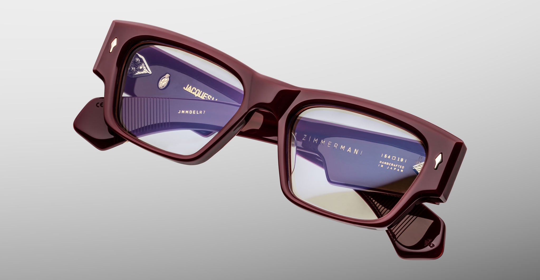 Jacques Marie Mage Zimmerman optical glasses in Bordeaux Empire red acetate with bold rectangular frame, clear lenses, and signature arrowhead front pins, angled front view