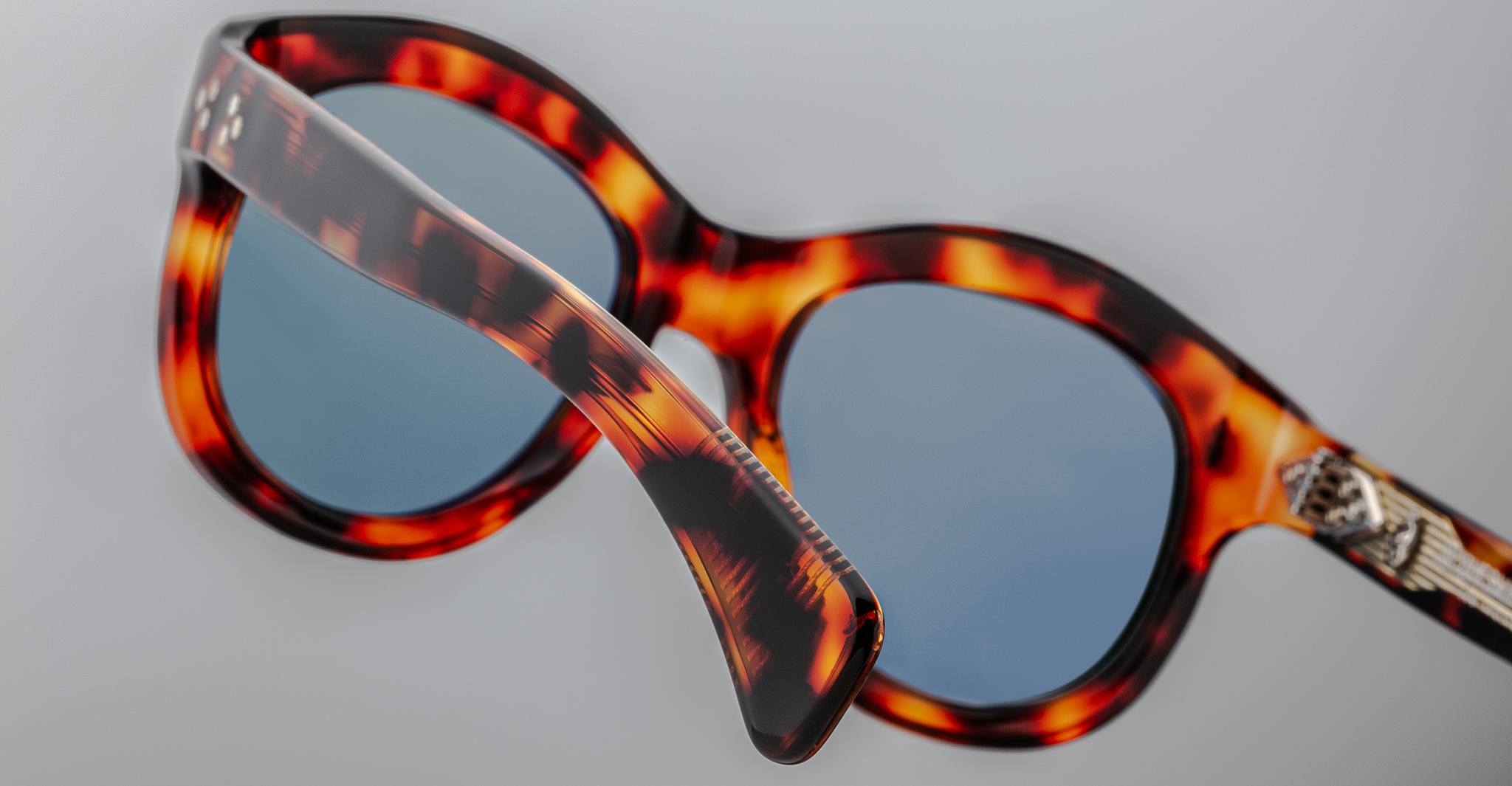 Close-up of Jacques Marie Mage Jennie sunglasses, tortoiseshell frame, blue lenses, and silver accents on the temples.