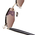 Close-up of Kuboraum P54 sunglasses featuring brown-tinted angular lenses, gold metal frame details, and a black arm in the foreground.