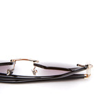 A close-up of black sunglasses with gold metal bridge and accents, lying folded against a white background. The gradient lenses transition from dark to light.