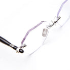 Close-up of rimless, hexagonal eyeglasses with thin metal bridge and black temple arms on a white background.